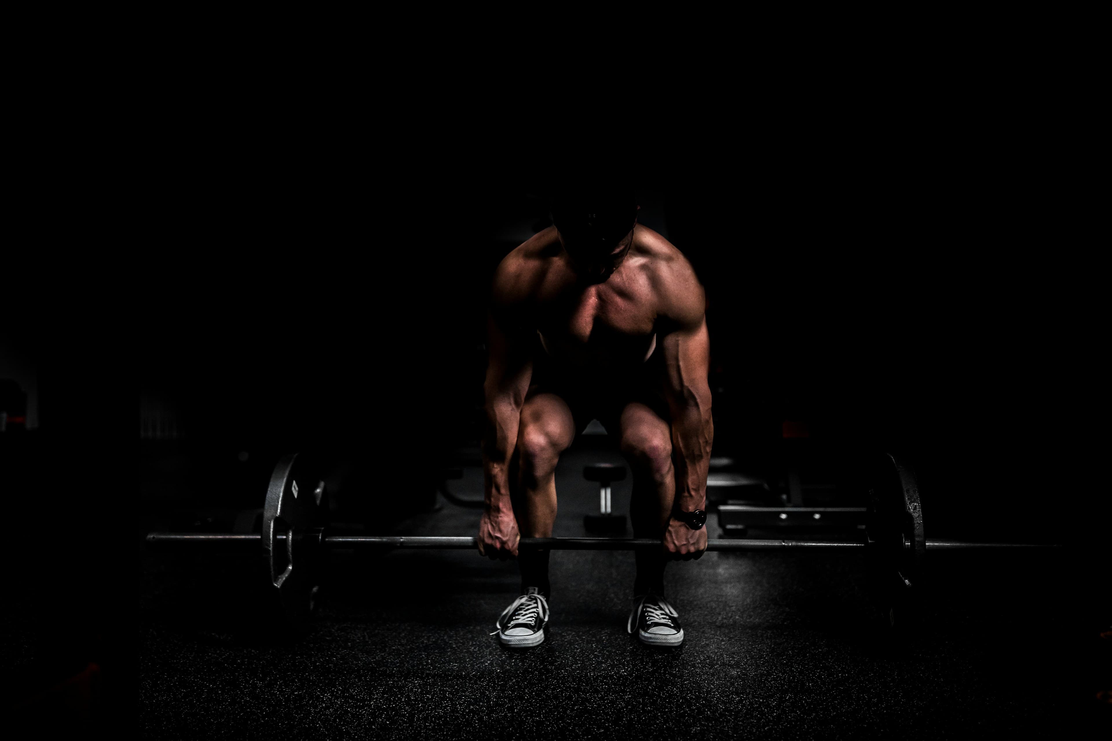 A training session underway: deadlift under a single hard light in a near-black studio